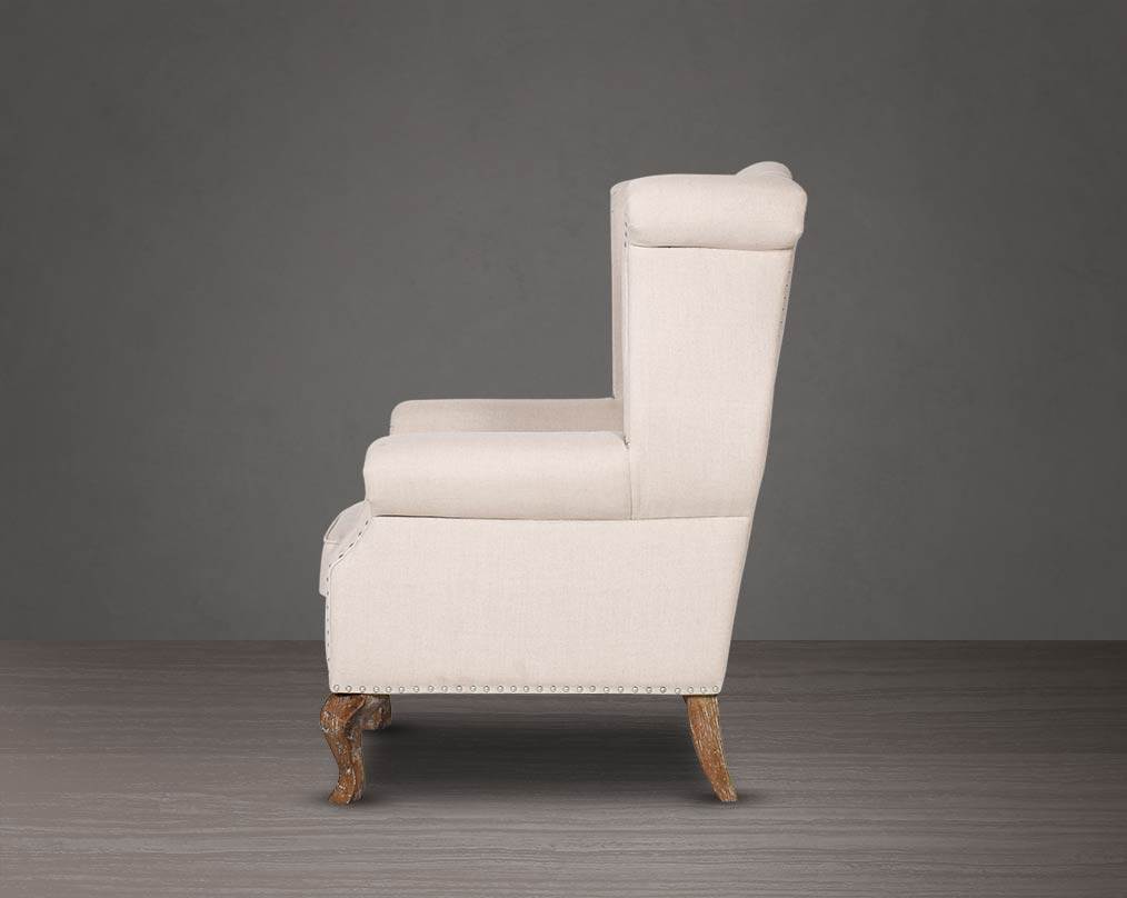 Wing arm chair upholstered in fabric with tufted back and stainless steel rivets and oak wood legs