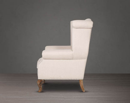 Wing arm chair upholstered in fabric with tufted back and stainless steel rivets and oak wood legs