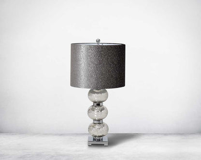 Table lamp with tinted crystal orbs on a silver-plated metal base with black translucent fabric shade.
