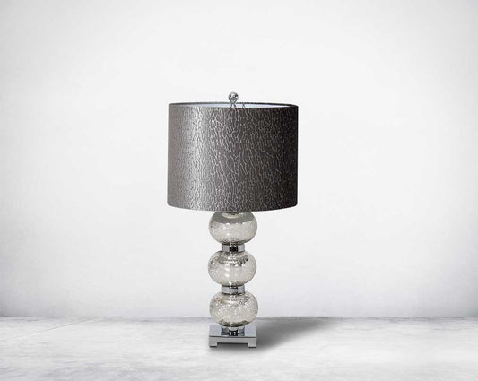 Table lamp with tinted crystal orbs on a silver-plated metal base with black translucent fabric shade.
