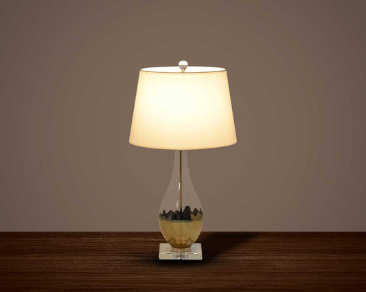Table lamp with metallic gold and glass decorative base with translucent fabric shade.
