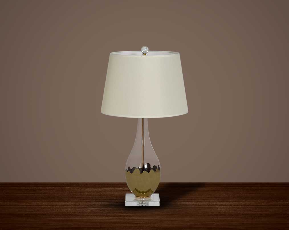 Table lamp with metallic silver and glass decorative base with translucent fabric shade.