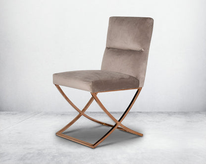 Dining chair upholstered in fabric with rose gold plated stainless steel legs in a cross design.