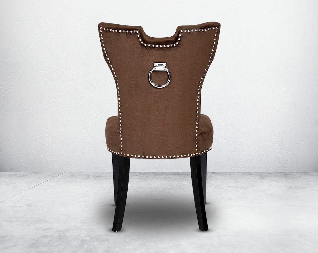Dining chair  back upholstered in fabric with legs in wood. Stainless steel decorative ring at the back with stainless steel rivets.