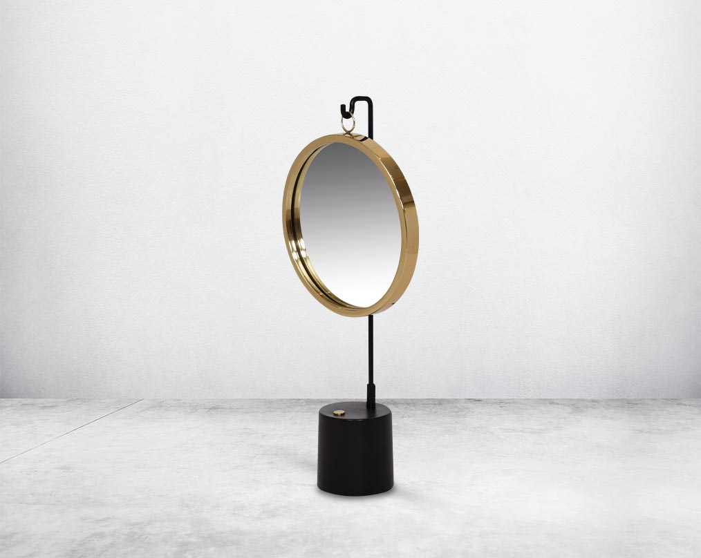 Round table dresser mirror suspended on a hook in shiny antique brass & matt black finished base. The look is very retro modern.