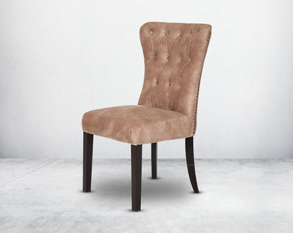 Dining chair upholstered in fabric with tufted back and birchwood legs. Stainless steel decorative ring at the back with stainless steel rivets on the sides.