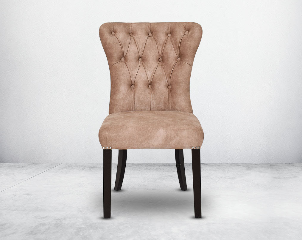 Dining chair upholstered in fabric  front with tufted back and birchwood legs. Stainless steel decorative ring at the back with stainless steel rivets on the sides.