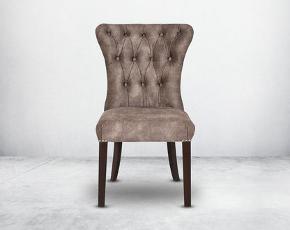 Dining chair front with upholstered in fabric with tufted back and birchwood legs. Stainless steel decorative ring at the back with stainless steel rivets on the sides.
