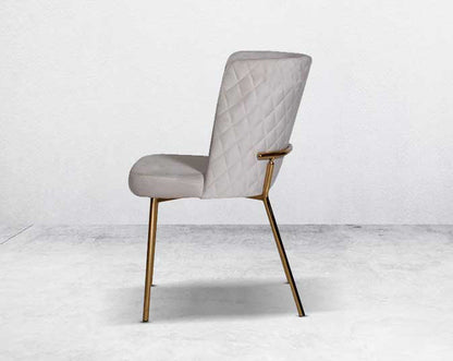 Minimalistically designed chair with criss-cross stitch padded fabric in gold finish stainless steel legs in contemporary design.