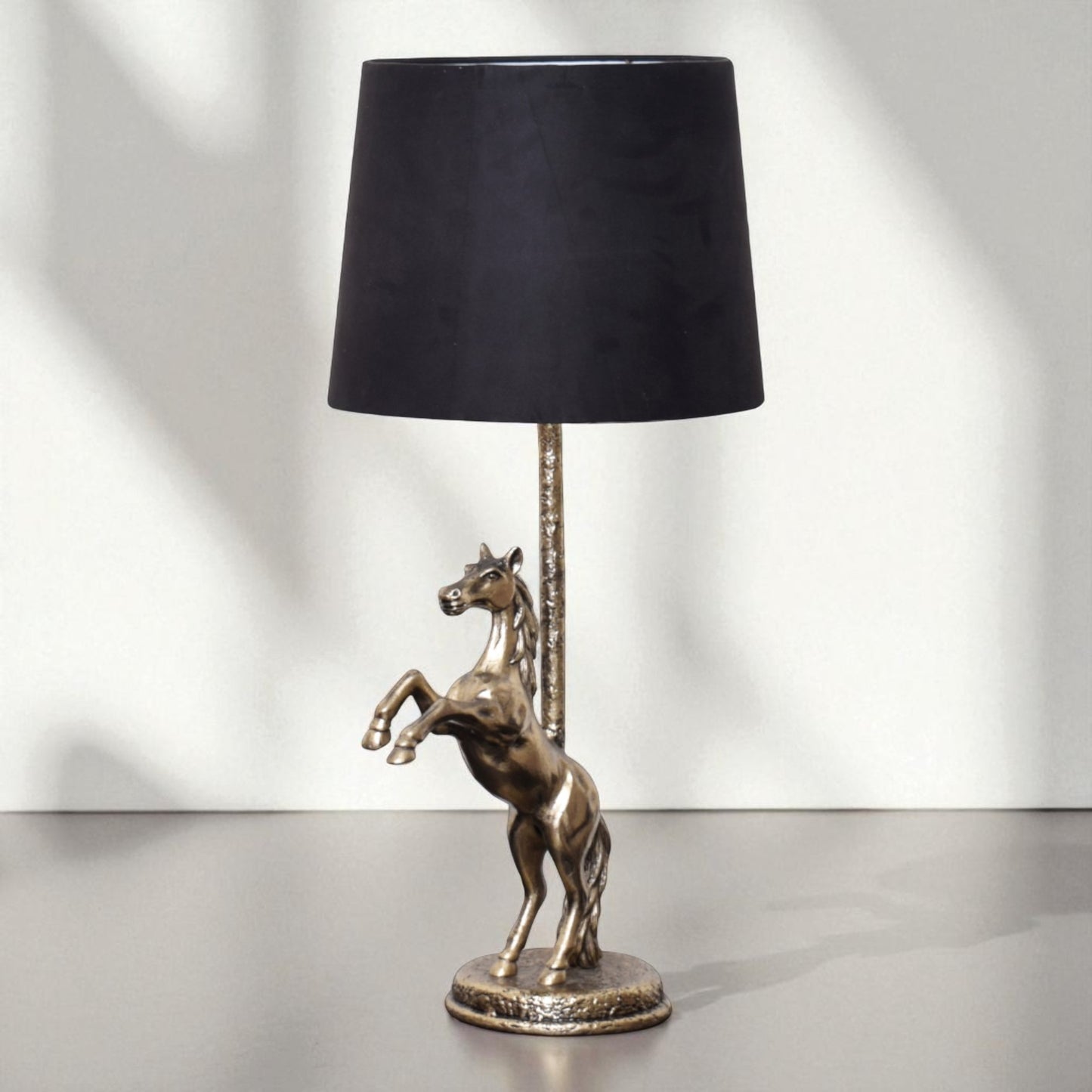 Table lamp with a horse sculpture base and black shade on a white background