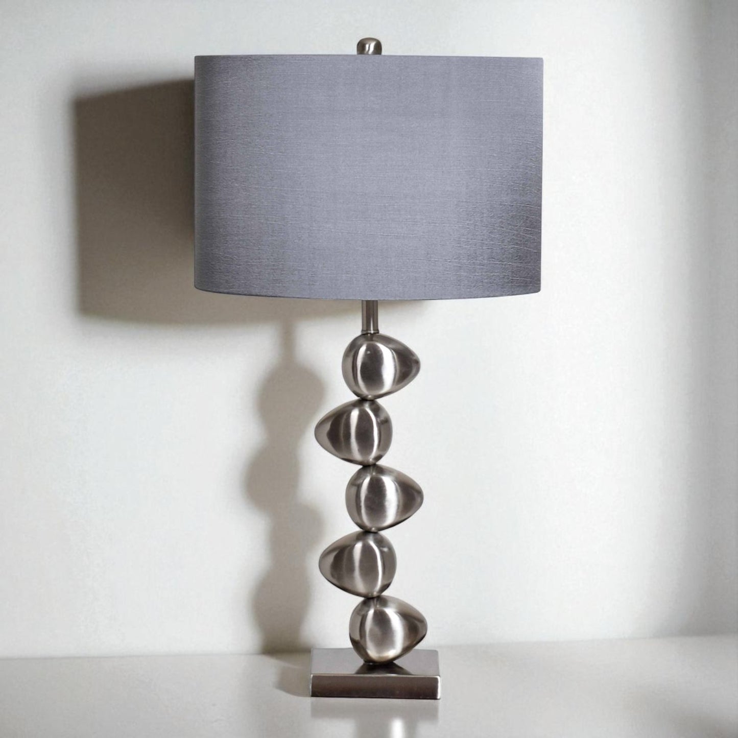 Table lamp with a gray shade and decorative base on a white background