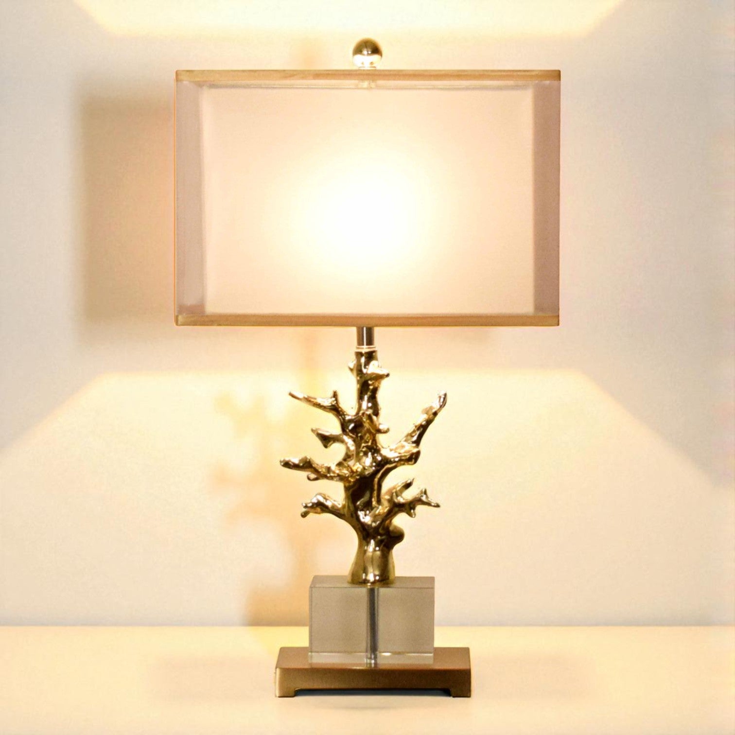 Decorative table lamp with a gold branch design on a neutral background