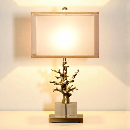 Decorative table lamp with a gold branch design on a neutral background