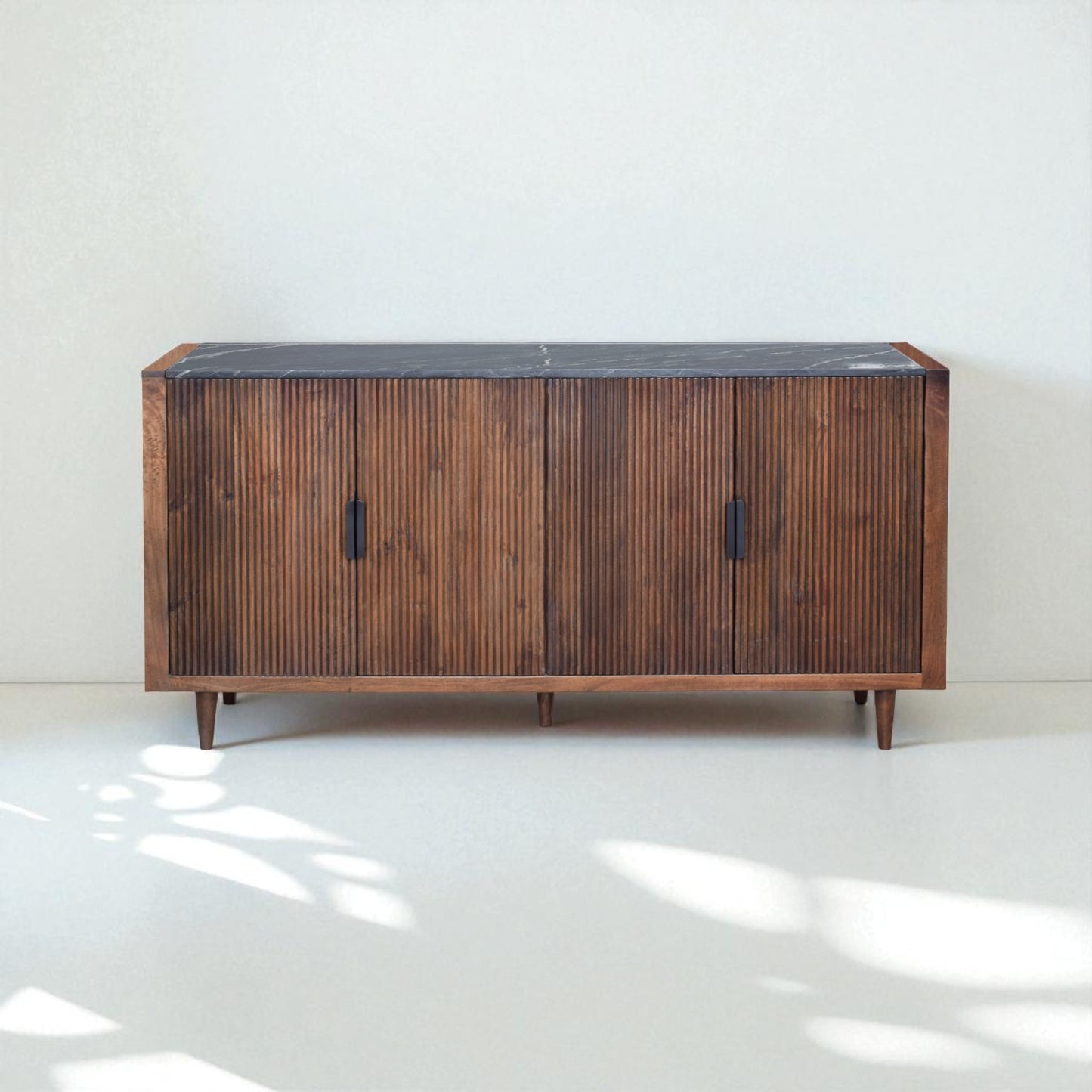Wooden sideboard with a black top on a white floor and light gray wall
