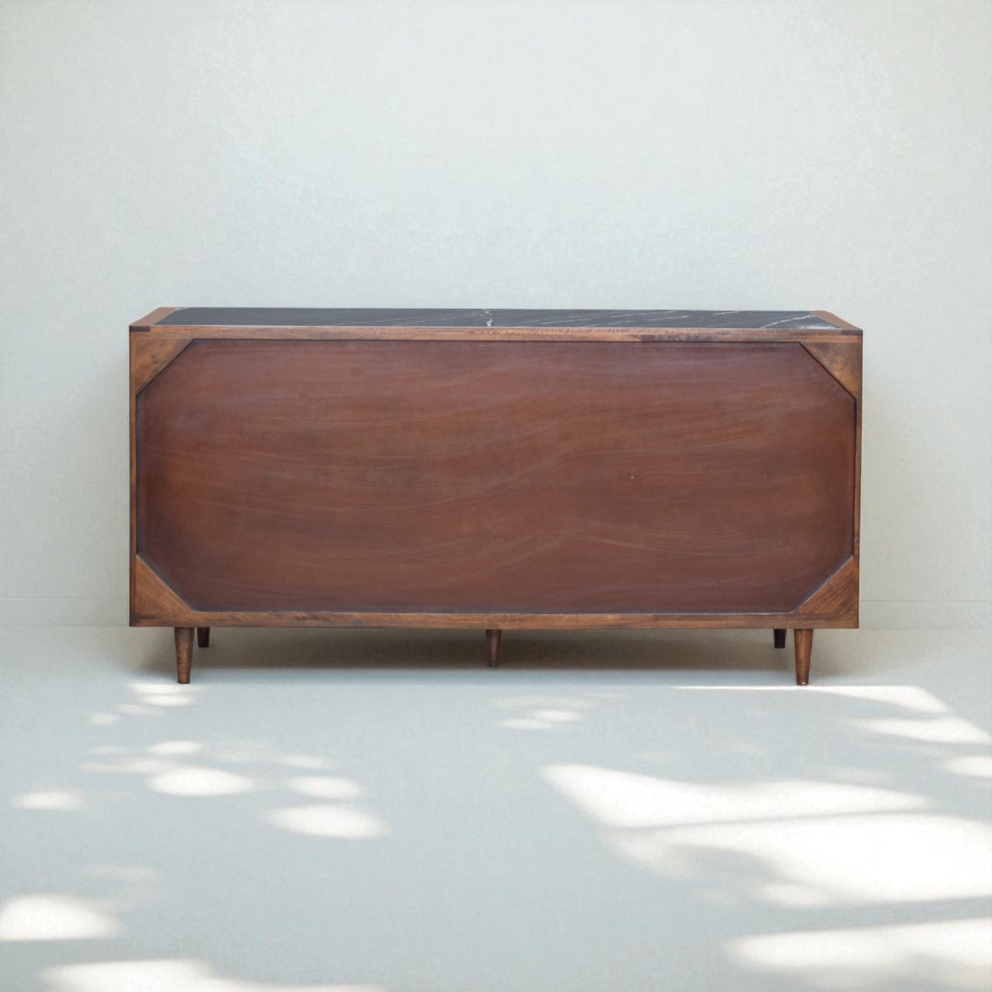 Wooden sideboard with a black top against a white wall
