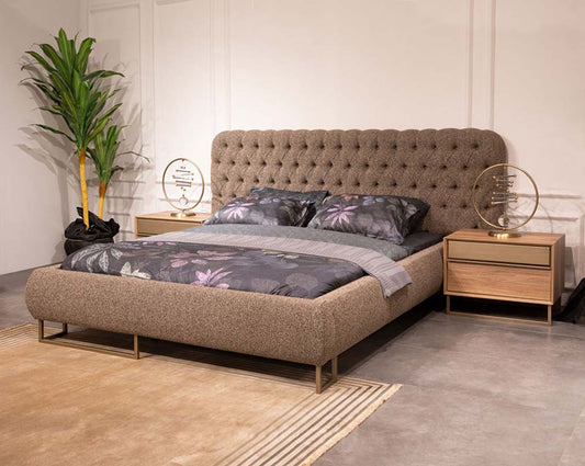 Beige upholstered bed with floral bedding in a bedroom setting.