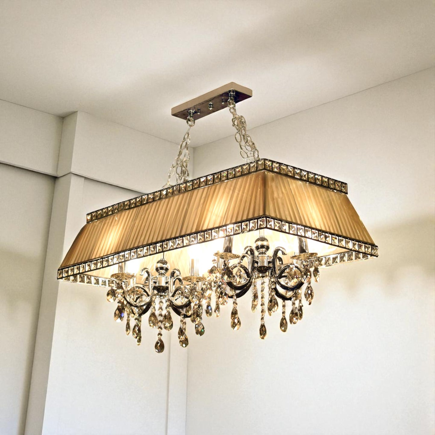 Luxurious chandelier with crystal accents and a gold shade in a room setting.