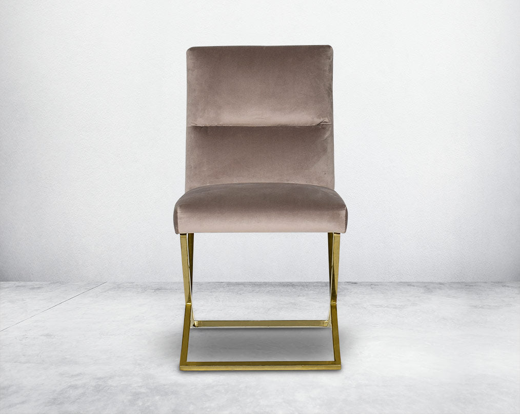 Dining chair with front  upholstered in fabric with gold plated stainless steel legs in a cross design.