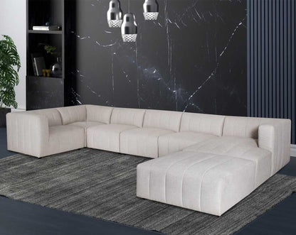 The L shaped modular sofa comes upholstered in regal beige fabric with vertical channel quilting & an ottoman to compliment