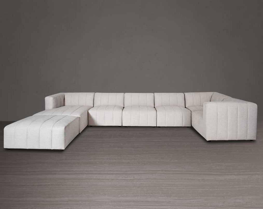 The L shaped modular sofa comes upholstered in regal beige fabric with vertical channel quilting & an ottoman to compliment - left side
