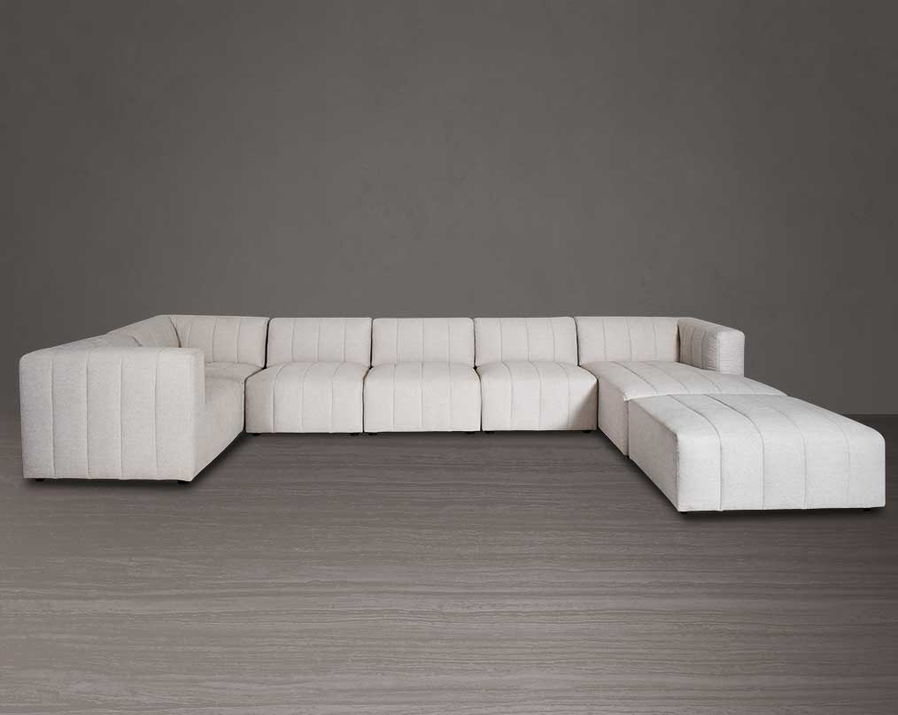 The L shaped modular sofa comes upholstered in regal beige fabric with vertical channel quilting & an ottoman to compliment - front view.