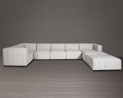 The L shaped modular sofa comes upholstered in regal beige fabric with vertical channel quilting & an ottoman to compliment - front view.