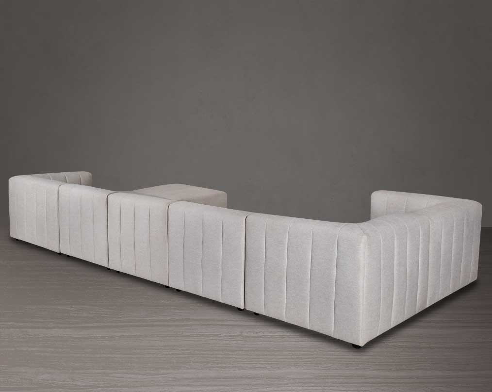 The L shaped modular sofa comes upholstered in regal beige fabric with vertical channel quilting & an ottoman to compliment - back view.