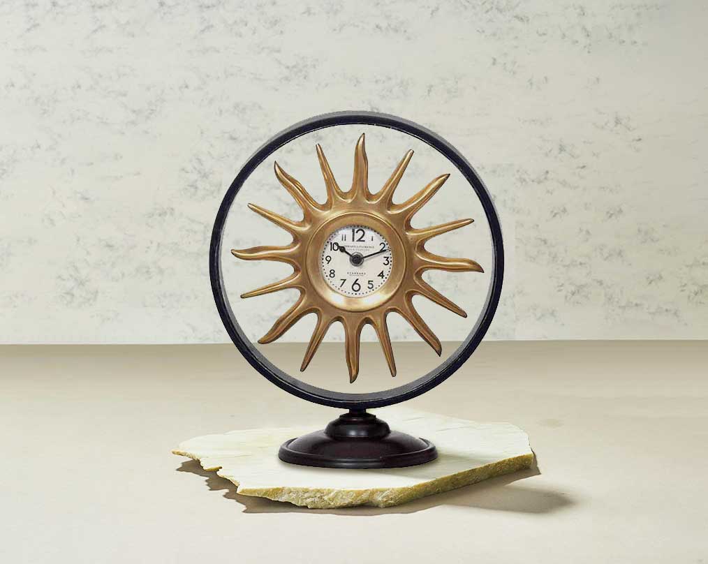 Round table clock in antique matt brass in sun ray design motif.